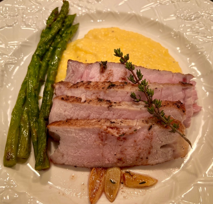 sliced pork chop on a bed of cheese polenta and asparagus